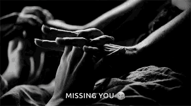 a black and white photo of a person holding another person 's hand with the words missing you above them