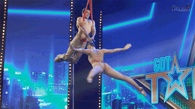 a couple of acrobats are performing on a stage with a got talent logo in the background