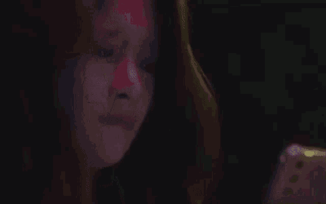 a woman is holding a glow in the dark stick in her hand .