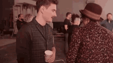a man in a plaid vest talks to a woman in a leopard print coat
