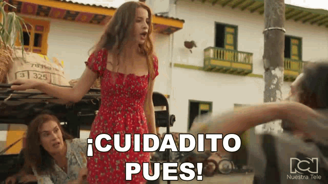 a woman in a red dress says " cuidadito pues " in front of a building