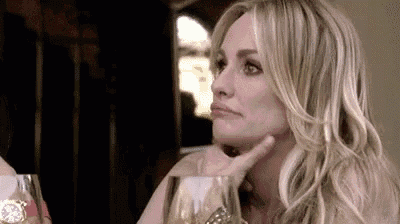 a woman is sitting at a table with a glass of wine and a watch .