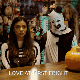 a woman standing next to a clown holding a camera with the words love at first fright below her