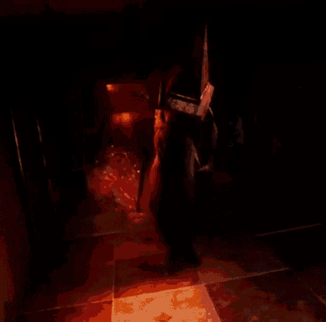 a person is walking through a dark hallway with a red light behind them .