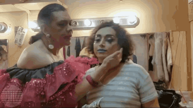 a woman is getting her makeup done in a dressing room