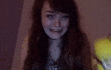 a woman with long hair is crying and smiling in a dark room
