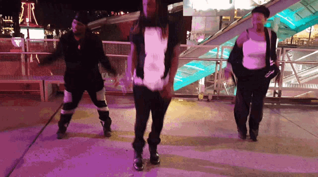 a group of people are dancing in front of a roller coaster