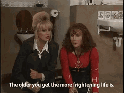 two women are sitting on the floor in a bathroom .