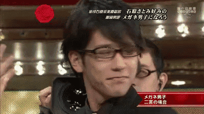 a man wearing glasses is being hugged by another man in a video