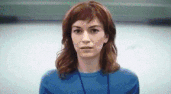 a woman in a blue sweater is looking at the camera .