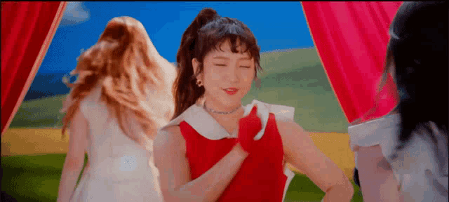 a woman in a red dress is standing in front of a red curtain .