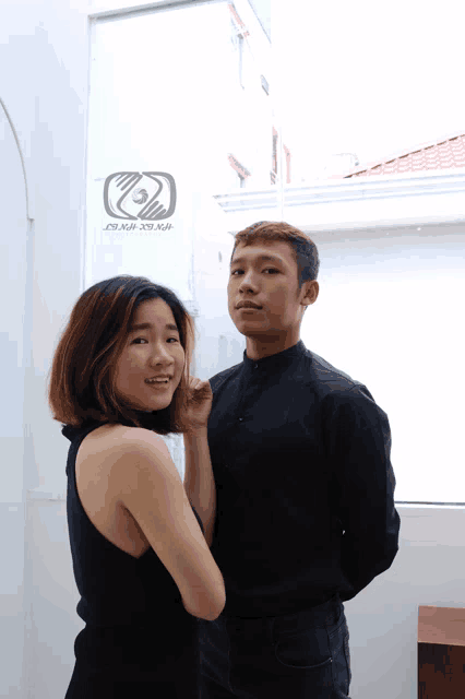 a man and a woman are standing next to each other with a sign on the wall that says ' saigon design '