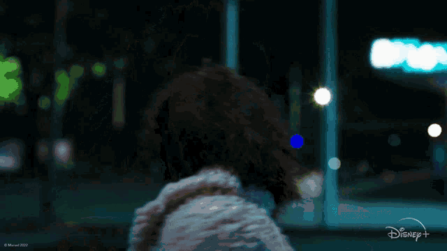 a woman in a fur coat is standing in front of a disney+ sign