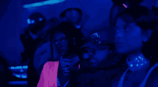 a group of people sitting in a dark room with a man wearing a hat with the letter a on it