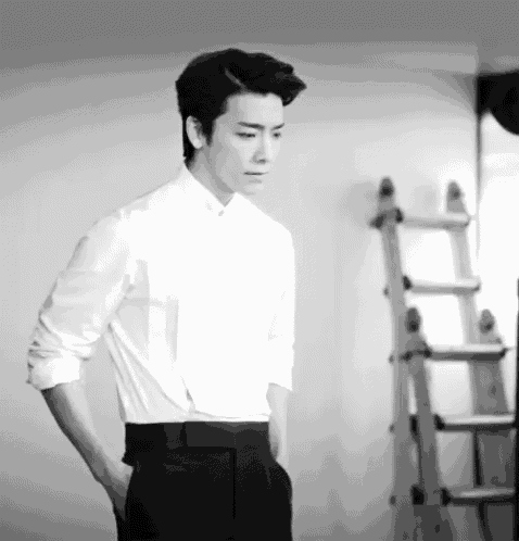 a black and white photo of a man in a white shirt and black pants