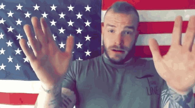 a man wearing a t-shirt that says the line holds his hands up in front of an american flag