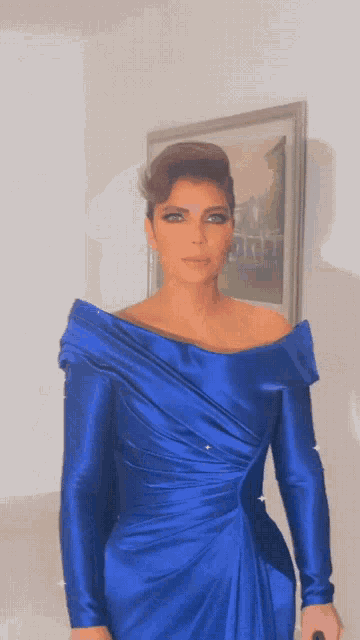 a woman in a blue dress stands in front of a picture frame