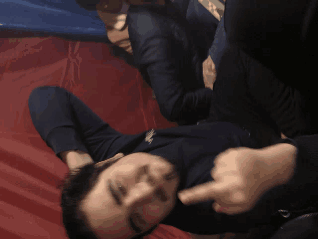 a man laying on a red and blue blanket giving the middle finger