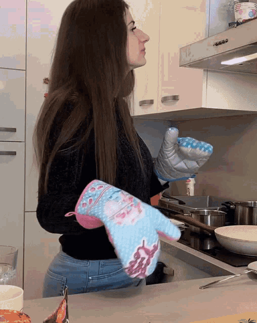 a woman wearing a blue and pink oven mitt with a bunny on it