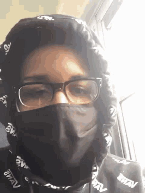 a person wearing glasses and a black mask with a hood on their head