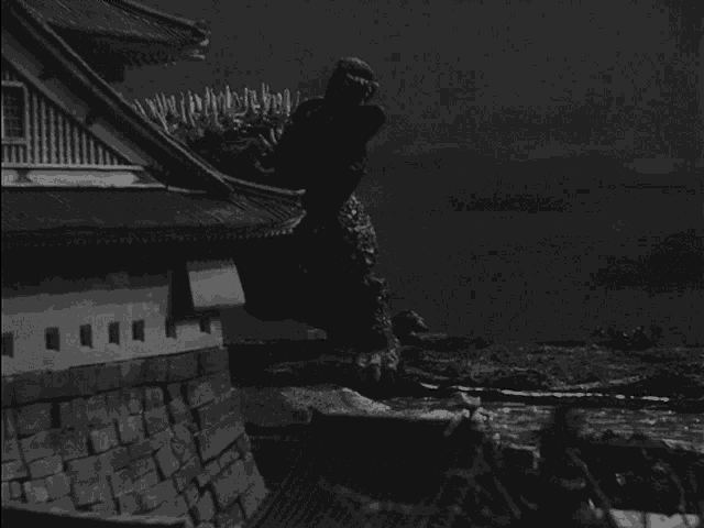 a black and white photo of a building with a monster on top