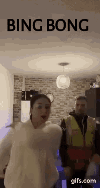 a man in a yellow vest is standing next to a woman in a white sweater and the words bing bong are on the ceiling