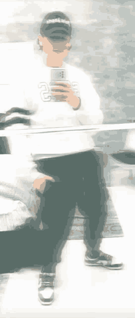 a person is taking a selfie in front of a mirror while wearing a hat .