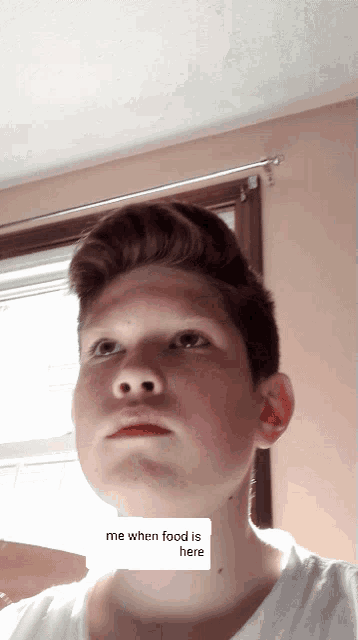 a young boy with a sticker on his neck that says " me when food is here "