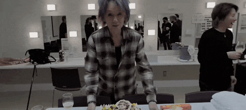 a woman in a plaid shirt is standing in front of a cake