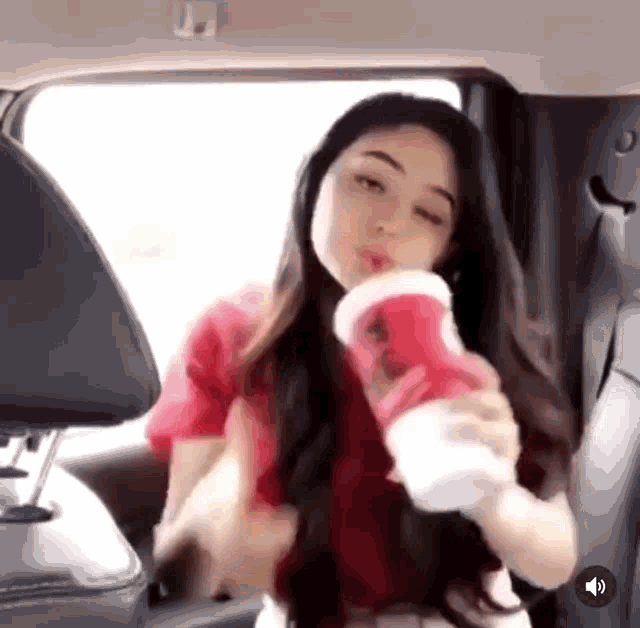 a woman is sitting in the back seat of a car drinking from a red cup .