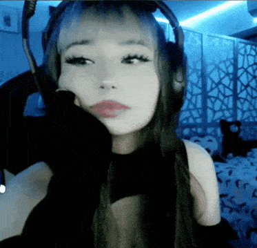 a woman wearing headphones and a black top looks at the camera