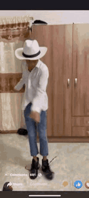 a man in a cowboy hat is dancing in a room .