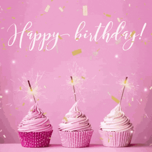three pink cupcakes with sparklers and the words happy birthday written in white