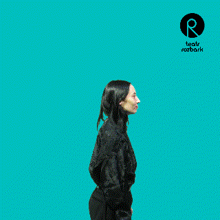 a woman stands in front of a blue background with a logo for teatr rozbark