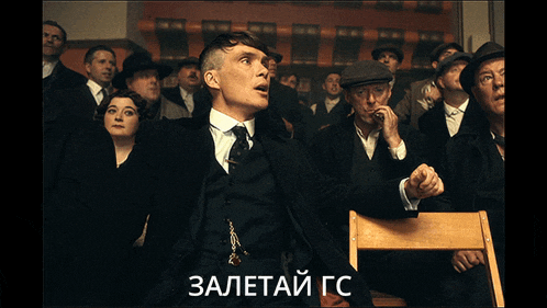 a man in a suit and tie stands in front of a crowd with a caption in russian that says " zaletai go "
