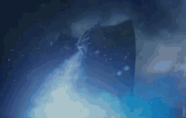 a dragon is flying through a cloud of blue smoke in the dark .