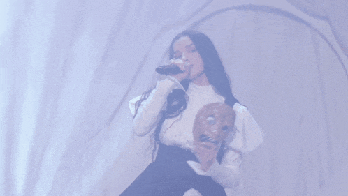 a woman in a white dress is singing into a microphone