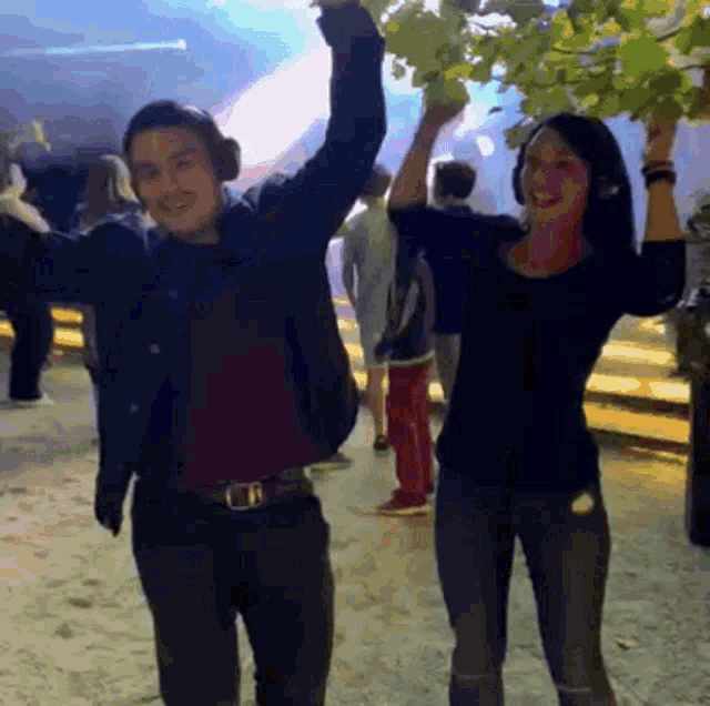 a man and a woman are dancing with their arms in the air while wearing headphones