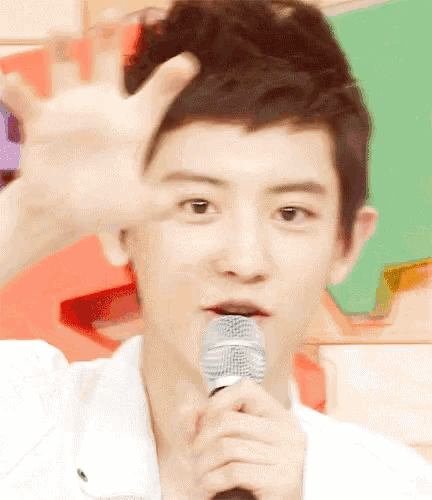 a young man is holding a microphone and making a hand gesture