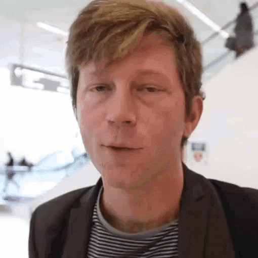 a man wearing a suit and striped shirt is looking at the camera