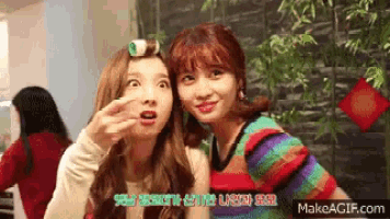 two girls are making funny faces while sitting next to each other and one has a roller in her hair .