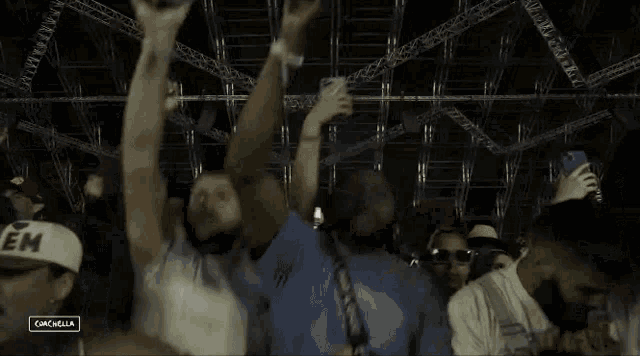a group of people are standing in a crowd with their arms in the air and a sign that says campella