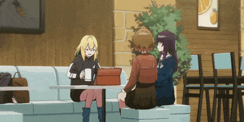 three girls are sitting at a table in a cafe
