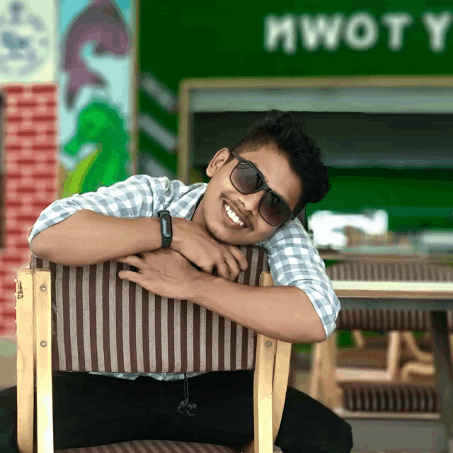 a man wearing sunglasses sits in a chair with his head resting on his arm