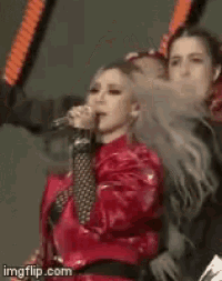 a woman in a red jacket is singing into a microphone