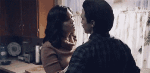 a man and a woman are kissing in the kitchen .