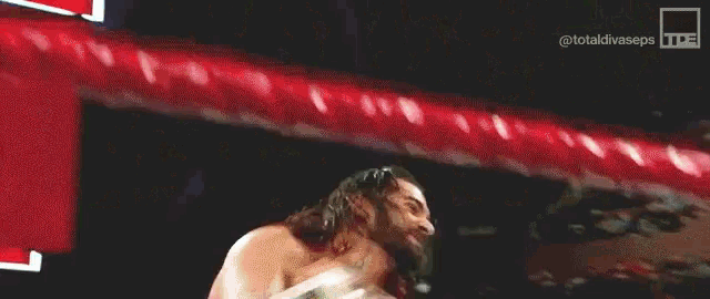 a wrestler is holding a sign that says burn down in front of a crowd of people .