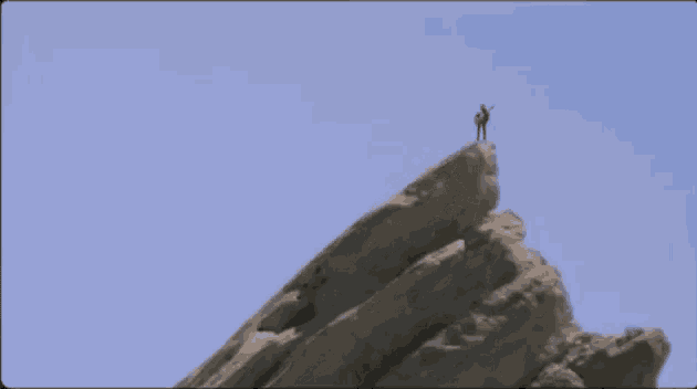 a person stands on the top of a rocky mountain