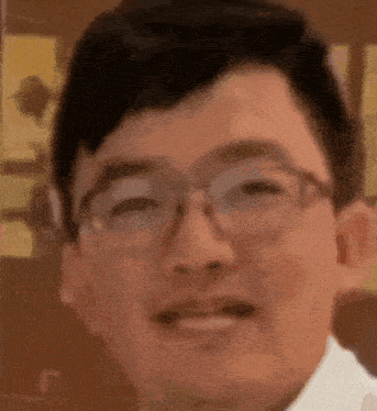a close up of a man 's face wearing glasses and a white shirt .