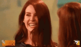 a woman is laughing while looking at herself in the mirror .